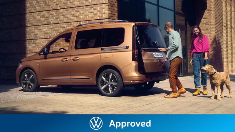 Una familia cerrando el maletero de su furgoneta Volkswagen Approved aparcada en el exterior