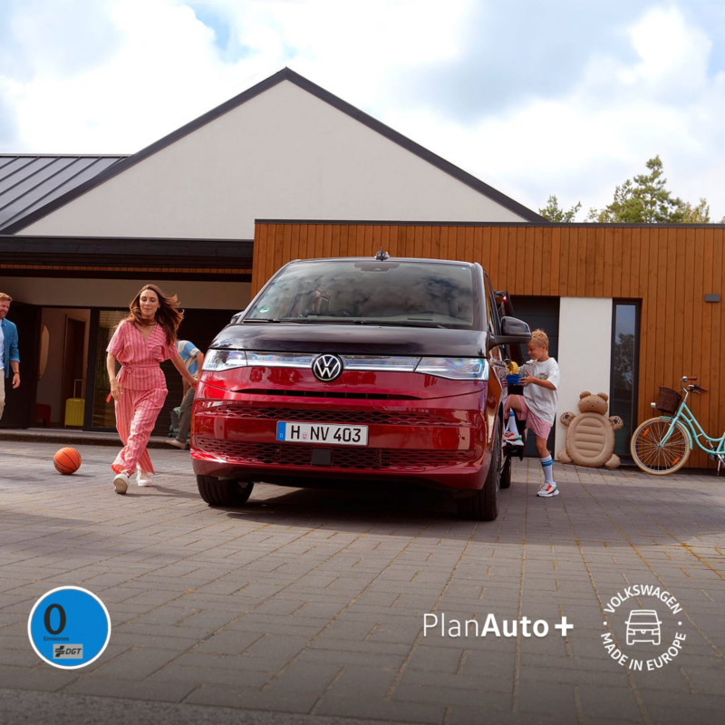 Una familia junto a una Volkswagen Multivan bicolor aparcada frente a una casa
