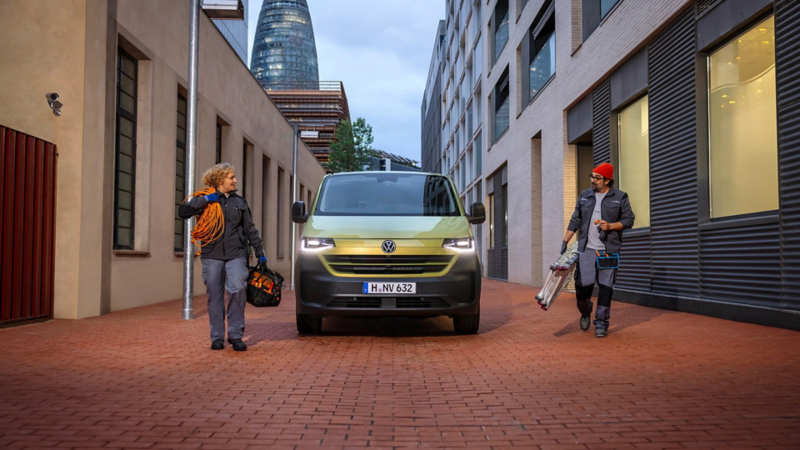 Un hombre y una mujer cada uno a un lado de una furgoneta VC verde
