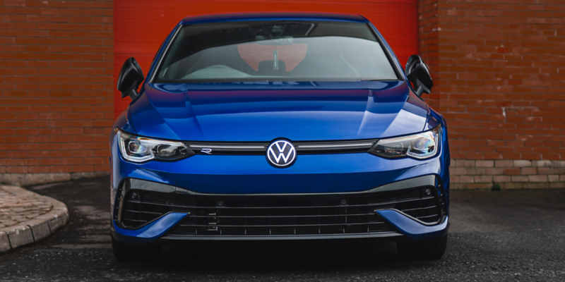 Volkswagen Blue Golf in Front of Red Brick wall