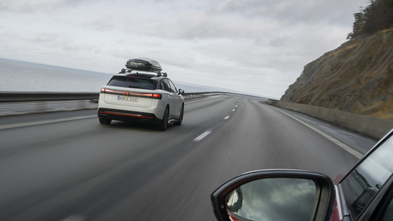 Blick aus einem ID. auf einen auf einer Küstenstraße fahrenden ID.7