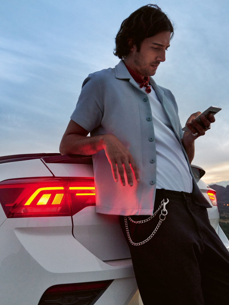 A driver leans on his Volkswagen with Mobility Guarantee