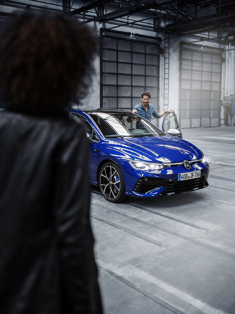 Mann in Jeanshemd steigt in blauen VW Golf R