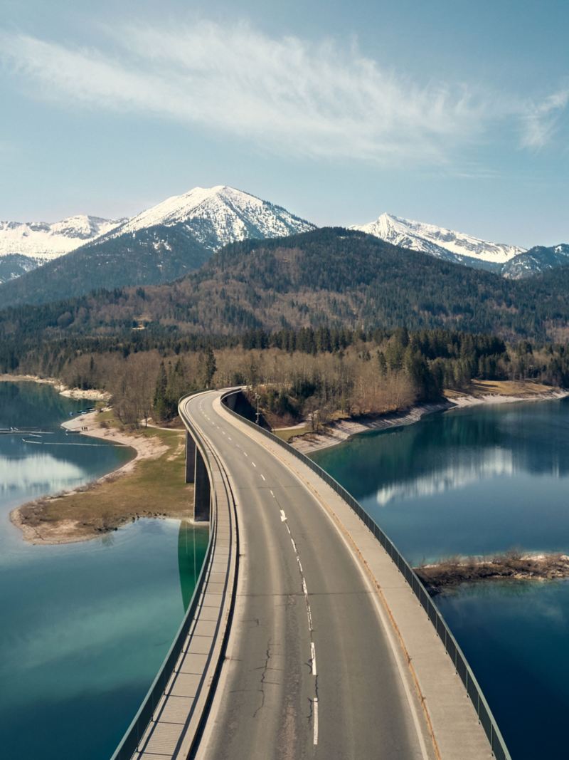 Una carretera sobre un cuerpo de agua que conduce a las montañas.