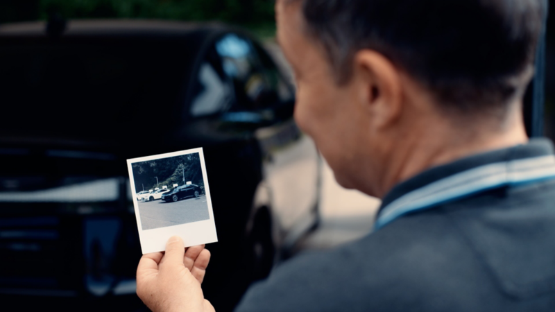 En mand kigger på et polaroid billede af sin gamle bil