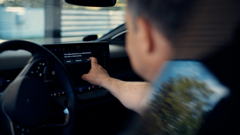 Mand sidder på førersædet og trykker på infotainment systemet