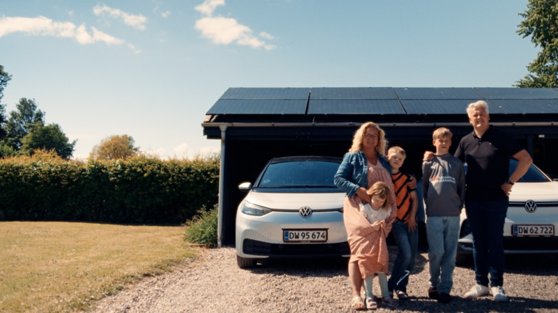 Peder og hans familie står foran deres to biler parkeret i carport