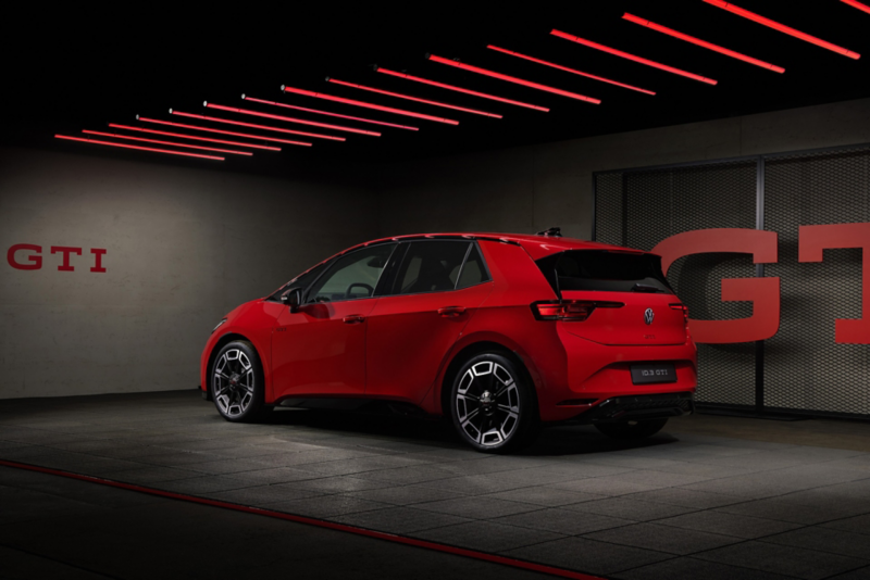 Röd Volkswagen ID.3 GTI sedd snett bakifrån i en mörk utställningsmiljö.