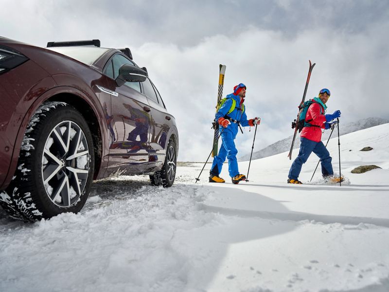 Zwei Männer fahren auf Skiern durch den Schnee, daneben steht der Volkswagen Touareg