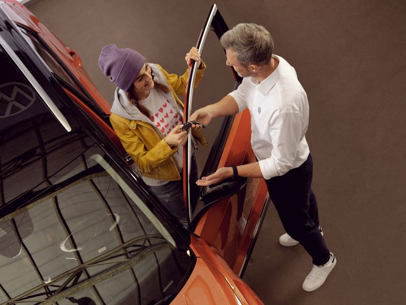 Un empleado del servicio técnico de Volkswagen le entrega a un cliente la llave de su Volkswagen