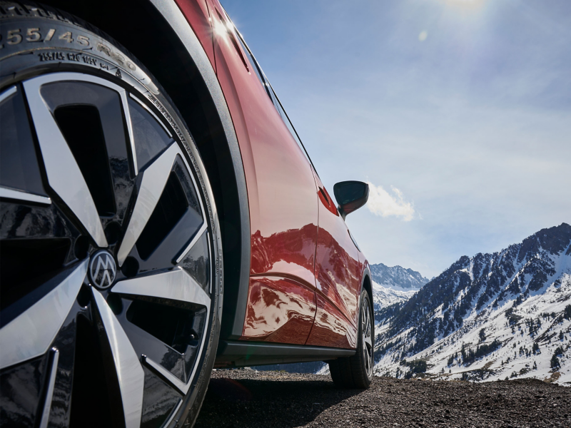 VW ID.5 GTX w zaśnieżonym górskim krajobrazie z lewym przednim kołem w centrum uwagi.