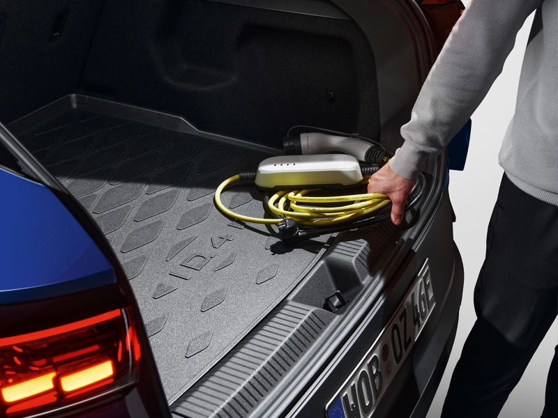 En Volkswagen fører tager sit Mode 2-ladekabel ud af bagagerummet på sin VW ID.4.