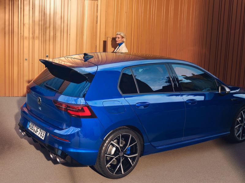 A woman stands next to her parked VW R Golf R