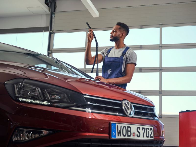 Volkswagen service employee checks windscreen wiper on a VW Golf Sportsvan in the workshop