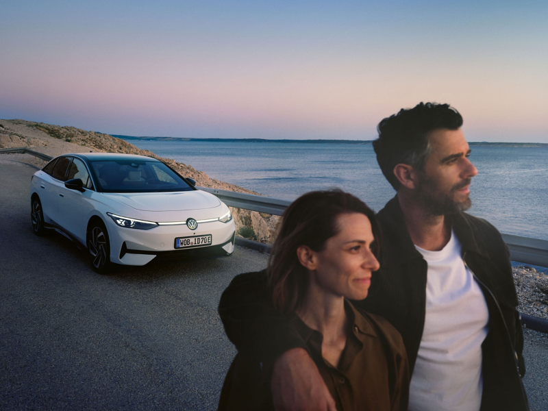 Paar neben VW E-Auto auf Straße beobachtet Sonnenuntergang