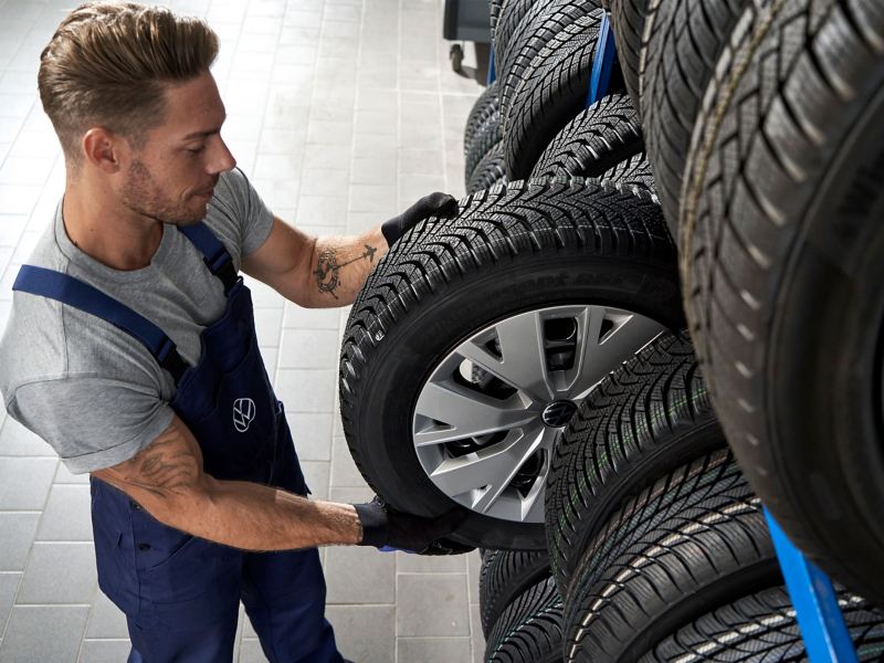 VW Servicemitarbeiter nimmt VW Reifen aus einem Regal – Rädereinlagerungs Service