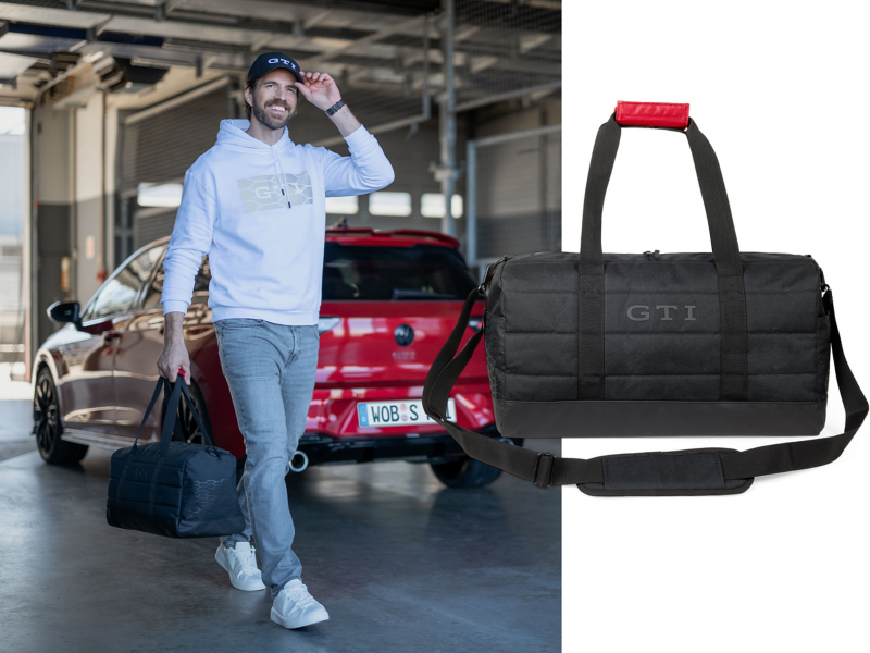 Hombre sonriendo con sudadera clara con capucha y logotipo GTI y gorra GTI, alejándose de un VW Golf GTI mientras lleva una bolsa deportiva GTI.
