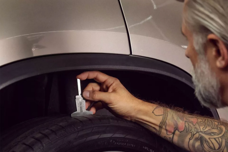 Un collaborateur du service entretien VW mesure la profondeur de la bande de roulement