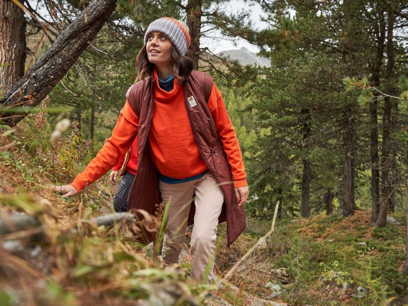 Eine Frau mit Wintermütze geht durch den Wald und genießt die Natur