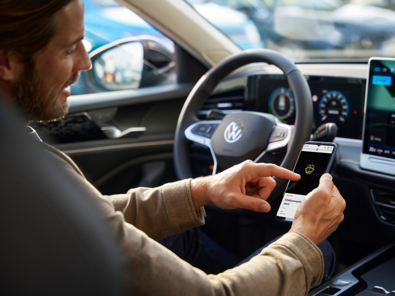 Kunde sitzt am Steuer eines VW Passat eHybrid und prüft VW Warnleuchten Hybridauto