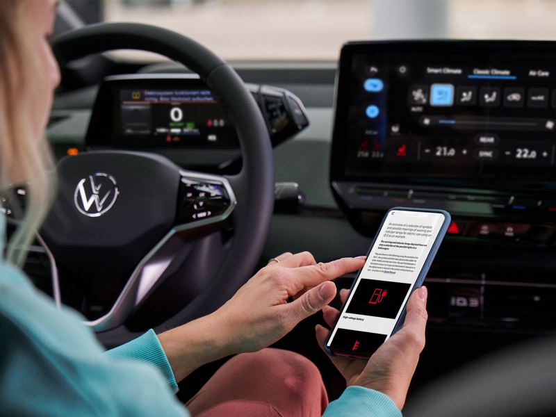 Customer sits at the steering wheel of a VW car and informs herself about warning lights