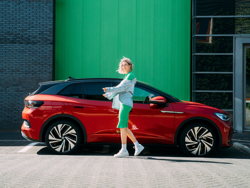 A woman stands in front of her parked VW ID. model in red