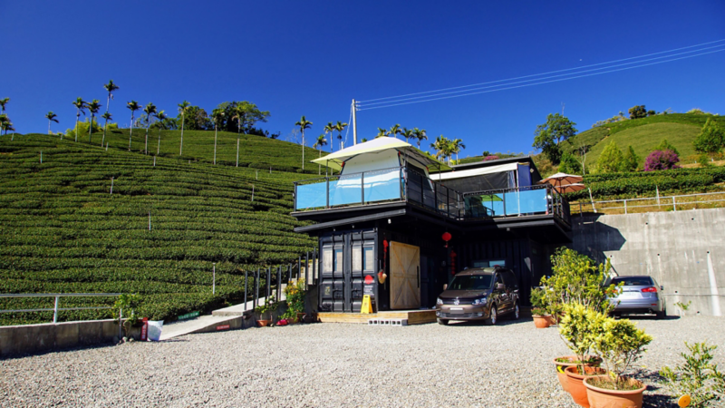 漠地棕色Caddy Maxi停在山上兩層樓的別墅民宿旁，後方是梯田狀的茶樹園