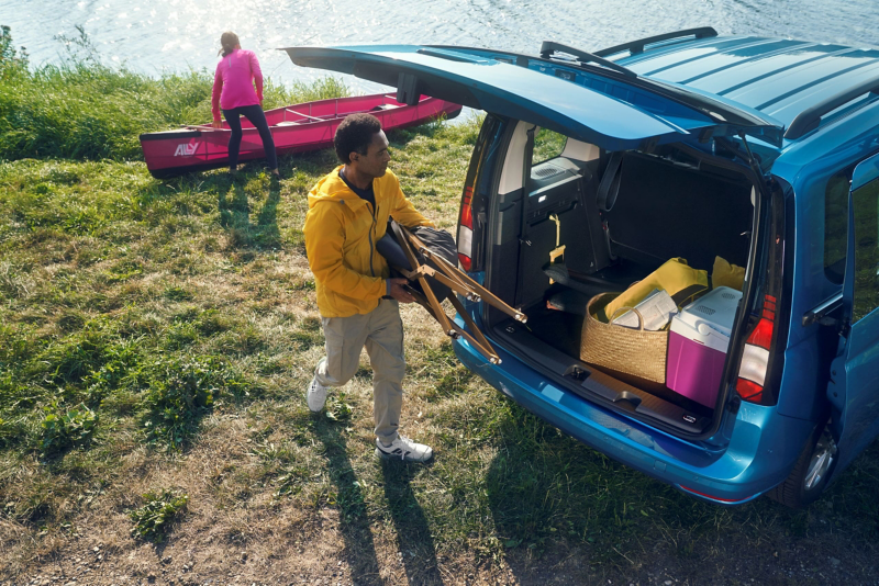 Mężczyzna pakujący krzesła do bagażnika Caddy