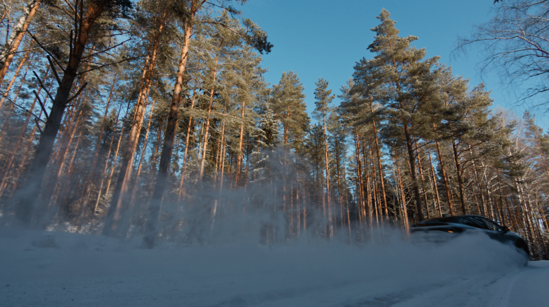 En bil kör på en väg, bilen syns knappt för snöröken bakom bilen