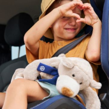 Una niña haciendo un corazón con sus manos dentro de un Volkswagen