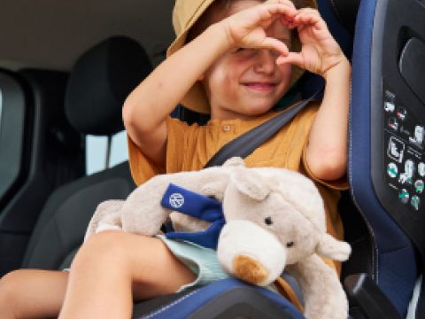 Una niña haciendo un corazón con sus manos dentro de un Volkswagen