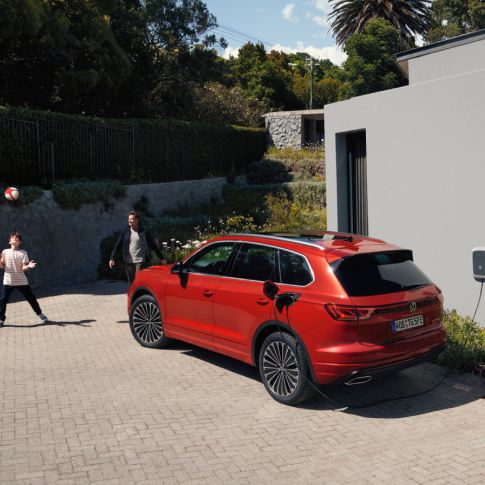 Un Volkswagen de color rojo estacionado en la calle conectado a carga