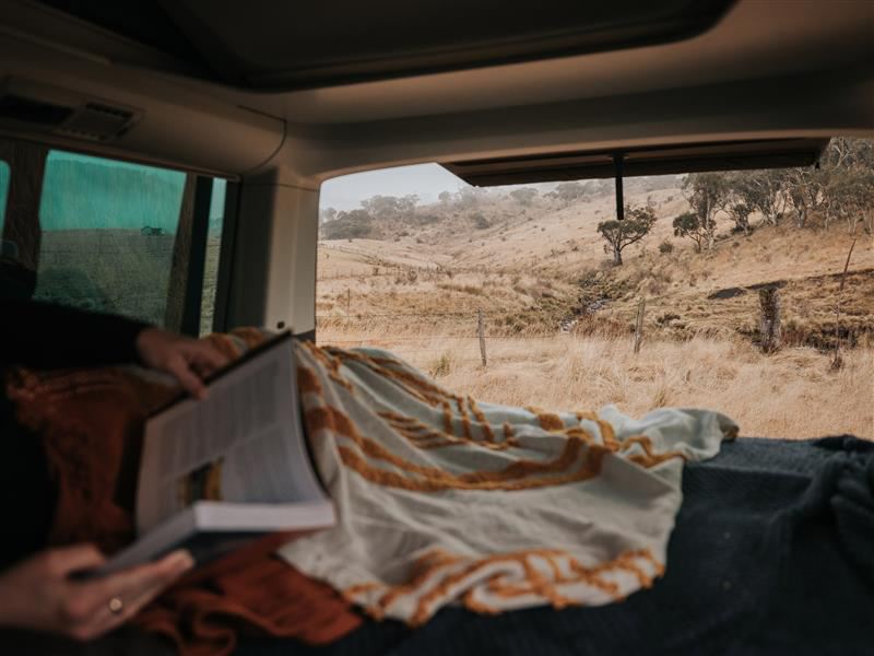Person reading book inside a California Campervan