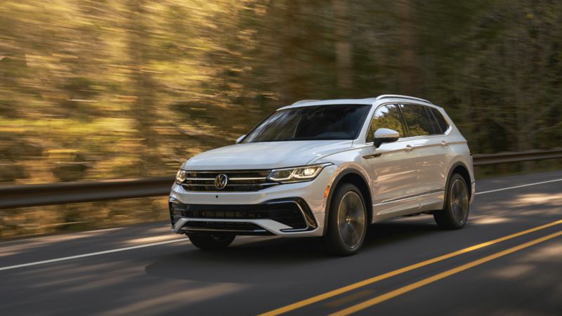 A Pure White 2022 Volkswagen Tiguan SUV with 4MOTION® All-Wheel Drive driving on a road.