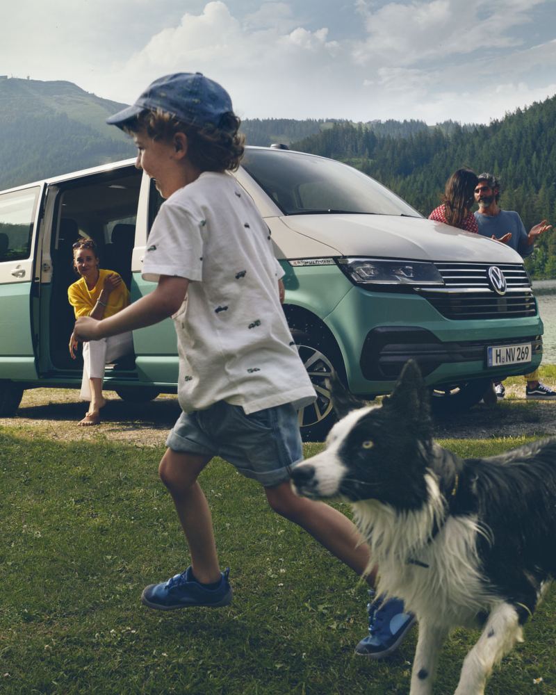 Una famiglia si rilassa in montagna con il proprio Volkswagen Multivan parcheggiato.
