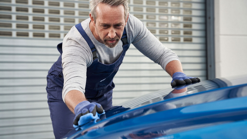 Un employé de VW services montre à sa cliente des pièces de carrosserie neuves ajoutées à sa voiture