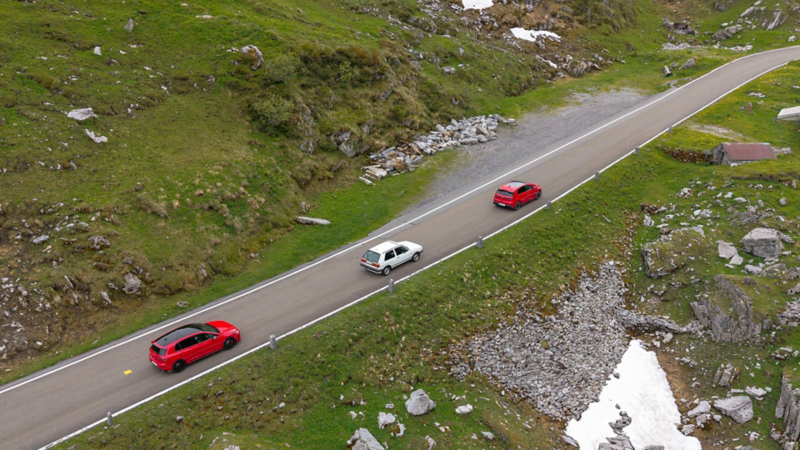 Tre generazioni della Volkswagen GTI su una strada di montagna nelle Alpi.