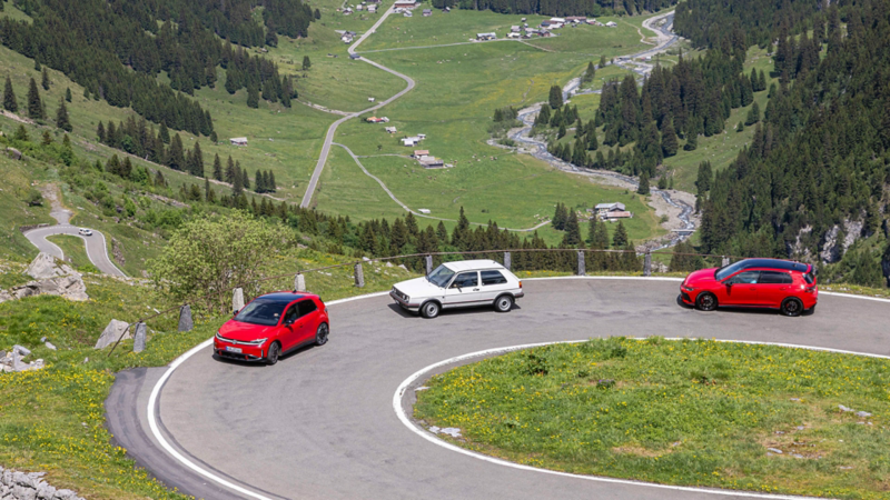 Tre generazioni della Volkswagen GTI su una strada di montagna nelle Alpi.