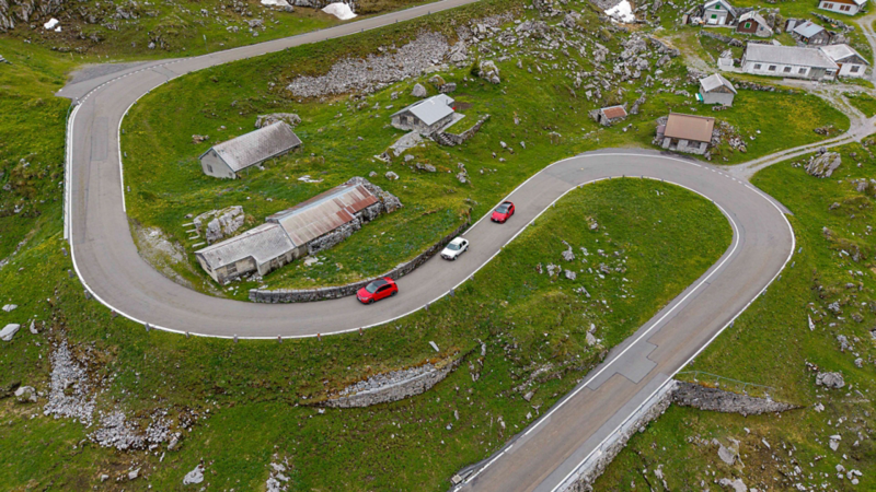 Tre generazioni della Volkswagen GTI su una strada di montagna nelle Alpi.
