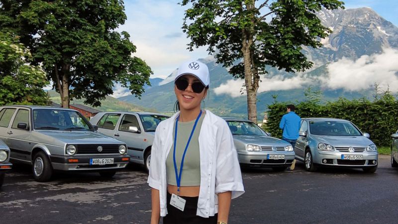 Viele unterschiedliche Golf Modelle stehen auf einem grossen Platz und eine Frau steht davor