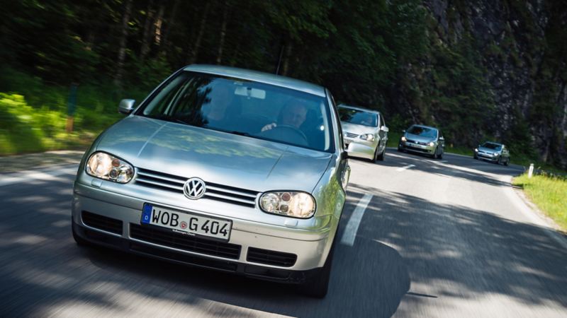 Mehrere Golf Modelle fahren über eine Landstrasse