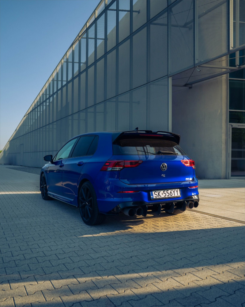 Granatowy, sportowy Volkswagen na tle szarej fasady.