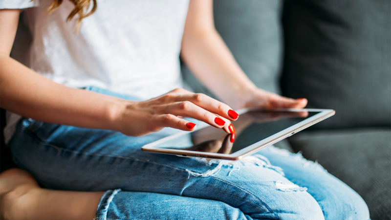 A woman sitting with a tablet on a sofa