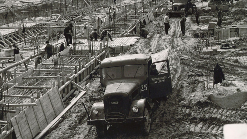Immagine in bianco e nero di un cantiere con un’auto vecchia in primo piano.