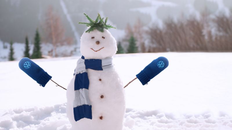 A small snowman wearing blue VW mittens.