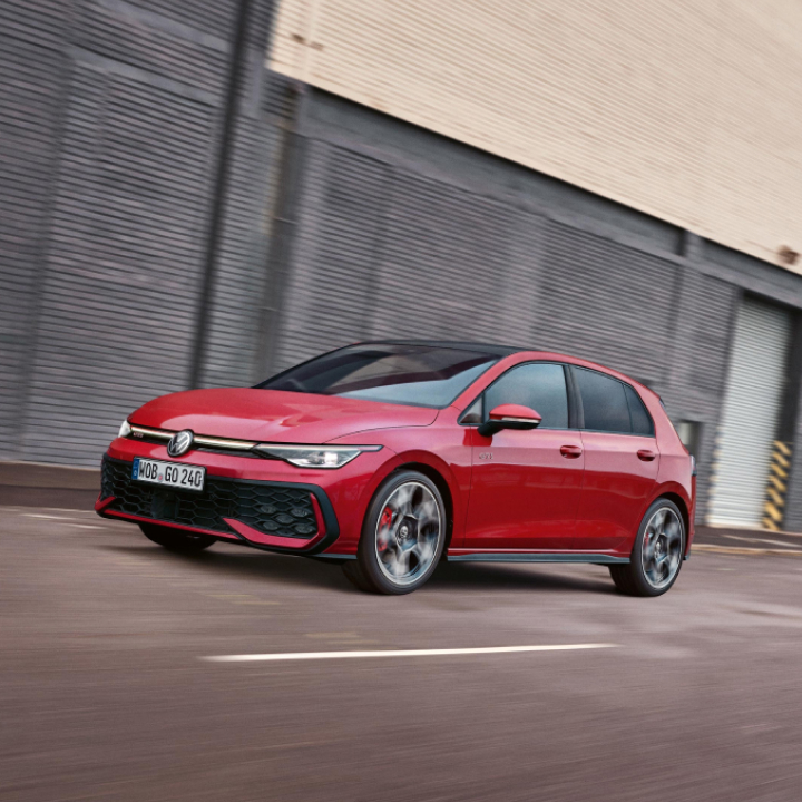 Un Volkswagen Golf GTI de color rojo circulando por una carretera en ciudad