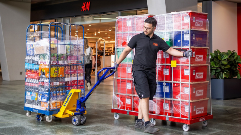 Des collaborateurs de 7Days transportent des marchandises dans un centre commercial.