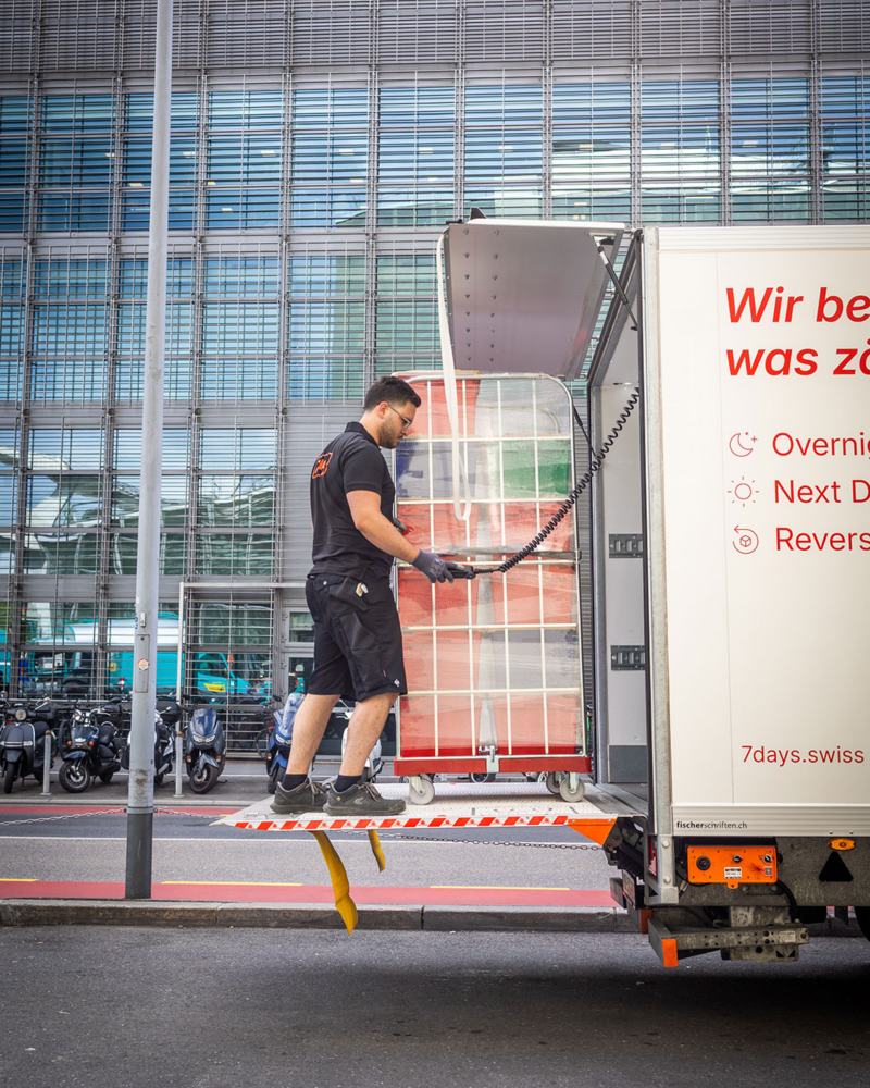 Transbordement de marchandises à l’aide d’un hayon élévateur sur un Volkswagen Crafter à chargement traversant de 7Days.