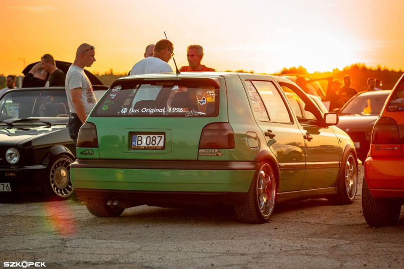 zielony samochód volkswagen, obok samochodu mężczyzni 