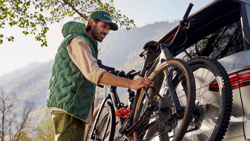 Un homme retire des vélos du porte-bagages arrière d'un VW California.